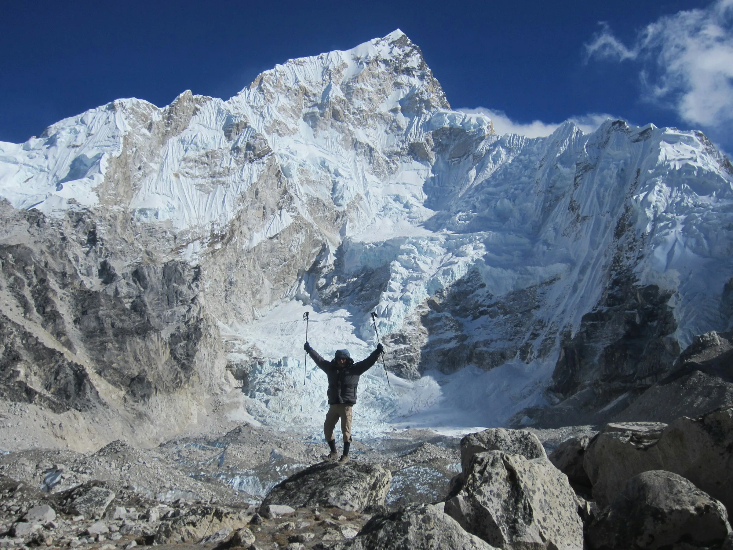 Trekker with arms raised below Everest and Nuptse